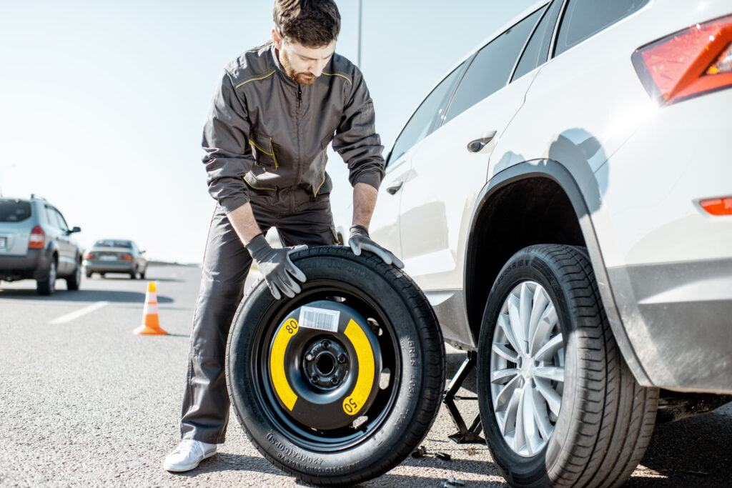Worker changing car wheel on the road